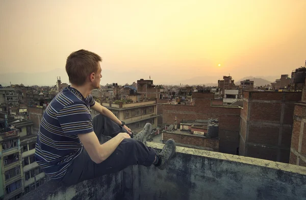 Jeune homme assis sur le mur — Photo