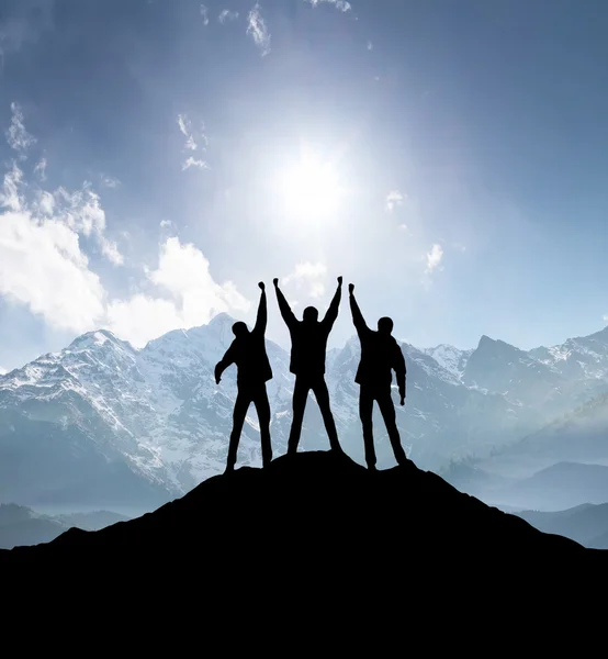 Silhuetter av team på bergstopp — Stockfoto