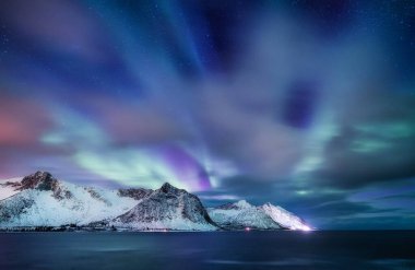 Norveç 'te Aurora Borealis. Dağların ve okyanusun üzerindeki yeşil kuzey ışıkları. Aurora ile gece kışı manzarası. Norveç 'te doğal fenomen.