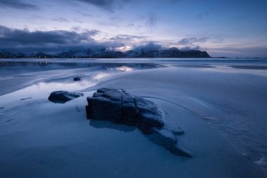 Norveç, Lofoten Adaları 'ndaki plaj. Gün batımında plaj ve bulutlar. Akşam vakti. Okyanus kıyısındaki kış manzarası. Norveç seyahati