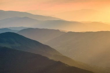 Gün batımında dağlar. Gün batımında dağ yamaçları. Dağlarda sis var. Güneş ışığı. Yazın doğal manzara..