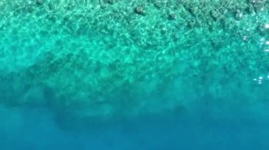 Arka plan olarak dalgalar ve gök mavisi su. Okyanus yüzeyindeki insansız hava aracının görüntüsü. Doğal yaz deniz manzarası. Su videosu arkaplanı.