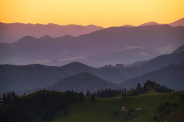 Bir dağ sırası manzarası. Yaz mevsiminde gün batımında manzara. Dağlık bölgedeki sisli tepeler. Seyahat görüntüsü. Bahar manzarası.