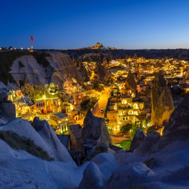 Goreme, Kapadokya, Türkiye. Dağdan akşam şehri manzarası. Parlak bir şehir ve berrak bir gökyüzü. Yaz mevsiminde manzara. UNESCO mirası. Tatil ve turizm.