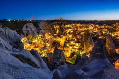 Goreme, Kapadokya, Türkiye. Dağdan akşam şehri manzarası. Parlak bir şehir ve berrak bir gökyüzü. Yaz mevsiminde manzara. UNESCO mirası. Tatil ve turizm.