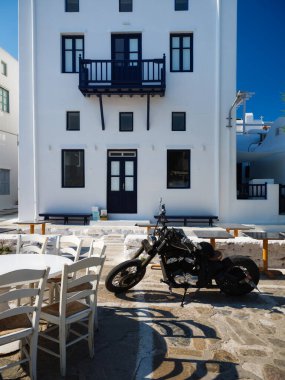 Yunanistan 'ın Mykonos caddesinde bir restoranın önünde motosiklet. Motosikletle seyahat etmek. Geleneksel Yunan evleri ve sokakları.