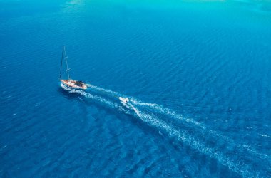 Gök mavisi denizdeki yatın havadan görünüşü. Akdeniz 'de şeffaf berrak su. Yaz tatilleri ve yat gezileri. Yaz gevşemesi.