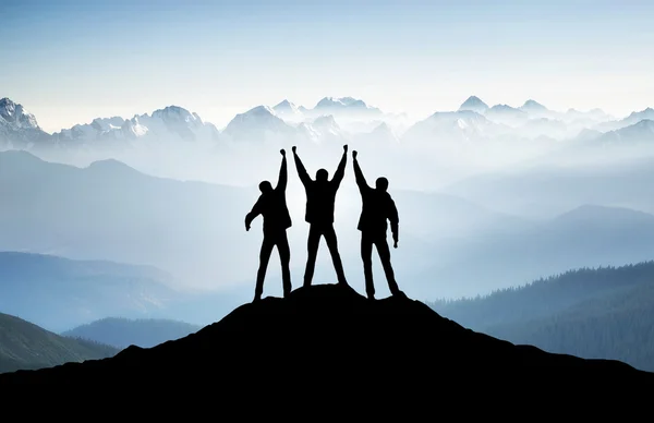 Team-Silhouetten auf Berggipfel. — Stockfoto