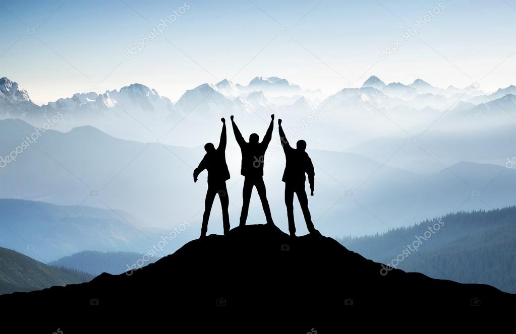 Team silhouettes on mountain top.