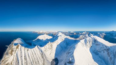 Flight over the mountains. Scandinavia. Aerial view on the Lofoten Islands, Norway. Wide panoramic view of the north. Natural winter landscape from air. Photo for postcards, backgrounds, wallpapers.