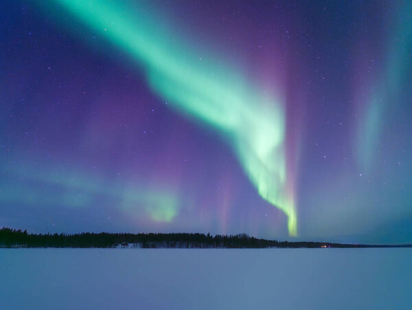 Aurora Borealis in Scandinavia. Northern lights over frozen lake. Starry sky. Glow on the sky. Winter landscape on the north. Panoramic picturesque view. Photo for background, wallpaper, postcards. 