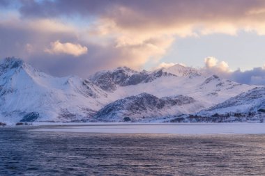 Norveç. Fiyortlarda doğa. Yüksek dağlar ve yansımalar. Fiyortta gün batımı. Kayaların üzerindeki bulutlar. Norveç 'te kış tatili ve seyahat. Arkaplan, duvar kağıdı, kartpostallar.