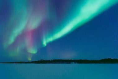 İskandinavya 'daki Aurora Borealis. Kuzey ışıkları donmuş göl ve ormanın üzerinde. Yıldızlı gökyüzü. Gökyüzünde parlıyor. Kuzeyde kış manzarası. Resimli bir manzara. Arkaplan, duvar kağıdı, kartpostallar için fotoğraf. 
