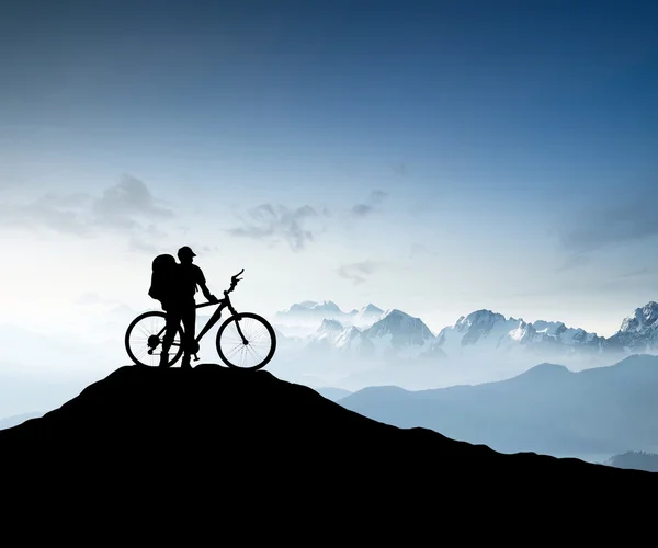 Silhouette of a bike tourist on mountain peak — Stock Photo, Image