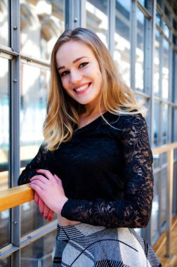 20 'li yaşlarda sarışın bir manken. Kısa etekli genç bir kadın. Tren istasyonu binasında fotoğraf çekimi.