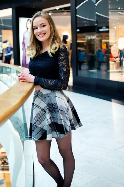 Alışveriş merkezinde fotoğraf çekimi. 20 'li yaşlarda sarışın bir kadın model. Kısa etekli, gülümseyen genç kadın..