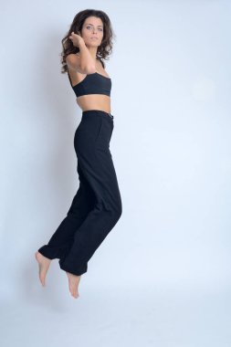 Stüdyodaki genç Polonyalı kadın. Siyah bluzlu, siyah pantolonlu, siyah saçlı zayıf bir kadın..