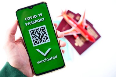 SARS-CoV-19 salgını sırasında seyahat ediyor. Geleneksel pasaport, maske, oyuncak uçak ve cep telefonunda Covid-19 pasaport uygulaması.