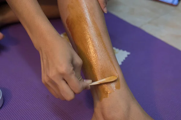 woman using wax for hair removal on leg