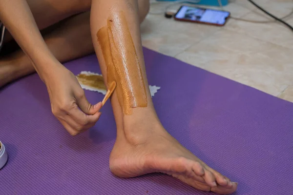 woman using wax for hair removal on leg