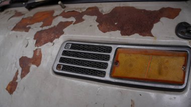 Pas tutmuş, boyalı, bulanık farlı ve eski tarz havalandırmalı eski bir araba gövdesine yakın çekim. Yaşlanmış, yıpranmış otomotiv detayları bozulma ve klasik araç tasarım elementlerini gösteriyor