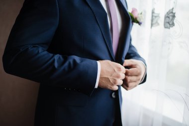 Ceketli bir adam, damat ceketini ilikliyor, damat ücretini ödüyor. 