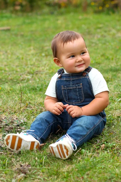 Pojken sitter på grönt gräs — Stockfoto