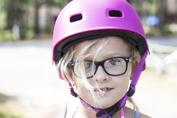 Criança com capacete de bicicleta rosa e óculos pretos — Fotografia de Stock