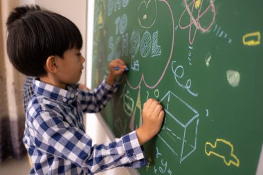 Asyalı küçük çocuklar karatahta yazar..