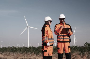 Mühendisler elektrik üretmek için rüzgar türbinlerini inceliyorlar..