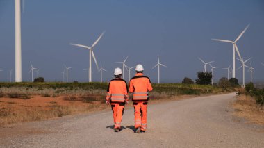 Mühendisler elektrik üretmek için rüzgar türbinlerini inceliyorlar..