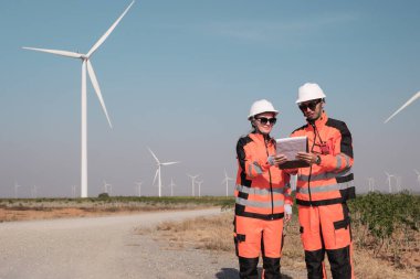 Mühendisler elektrik üretmek için rüzgar türbinlerini inceliyorlar..