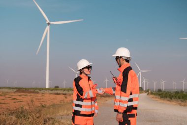 Mühendisler elektrik üretmek için rüzgar türbinlerini inceliyorlar..