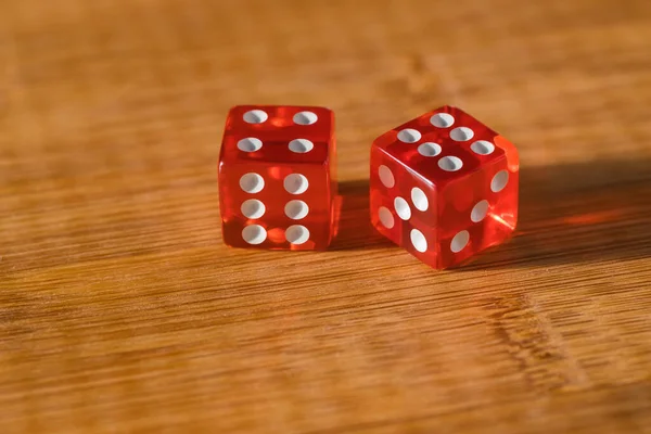 Two red glass dice on a wooden bamboo background. The result is four and six.