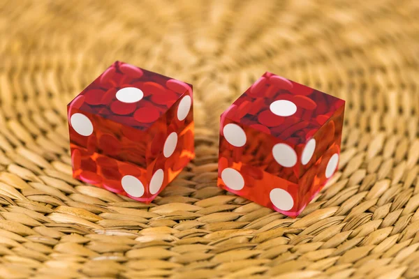 Two red glass dice on a wicker round rug. The result is \