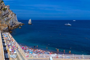 Yalta, Crimea - September 13, 2012: Beach and vacationers at the foot of the castle Swallow's Nest in Ai-Todor Bay.