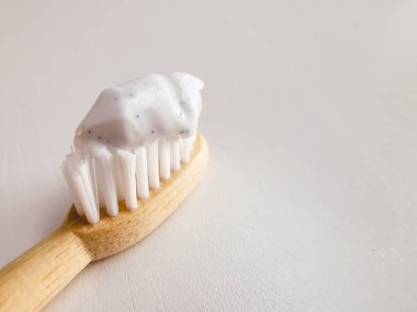 Micro plastic particles in a smear of toothpaste on a wooden toothbrush. Representation of the micro plastic problem in personal care products that damage nature. clipart