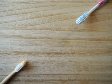 Plastik diş fırçası ve bambu bir diş fırçası ile tahta arka planda sürdürülebilir alternatif olarak plastik ücretsiz yaşam tarzı takas kavramı.