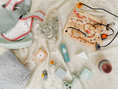 Sessiz, yumuşak renkte bebekler için cinsiyet ayrımı olmayan oyuncaklar. Tahta bloklar boncuk çerçeveli, diş çıkarma oyuncağı, önlük, boncuk. Düz yatıyordu. Cinsiyetsiz ebeveynlik.