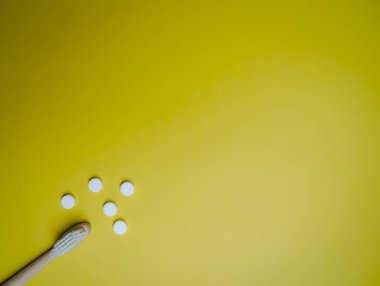 Bambu diş fırçası ve sarı arka planda diş telleri, plastiksiz takas. Sıfır atık yaşam tarzı.