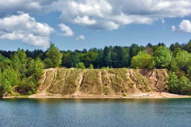 Güneşli bir günde bir orman gölünün dik kıyısı.