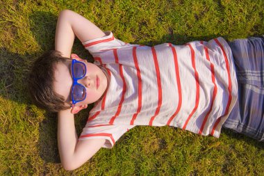 Yaz aylarında çim üzerinde güneşlenme Boywith güneş gözlüğü