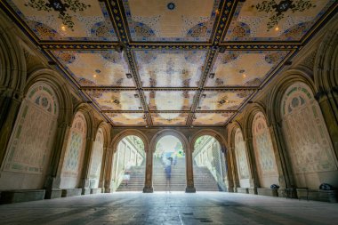 New York, Central Park 'taki Bethesda Terrace Çarşısı. Süslü fayanslı tavan ve büyük merdiven. Tarihi kemerlerin altındaki ziyaretçilerin yumuşak hareket bulanıklığı..