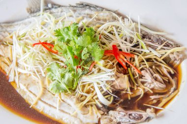 Beyaz arka planda soya soslu buğulanmış pomfret.