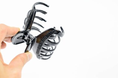 Elinde siyah plastik saç tokası olan bir kadın mücevher.