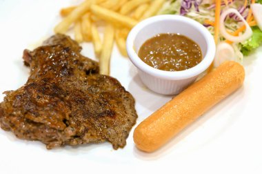 Biber Biberli Biftek, yanında patates kızartması ve sosis.