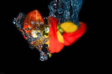 Siyah arkaplanda su sıçratan kırmızı biber.