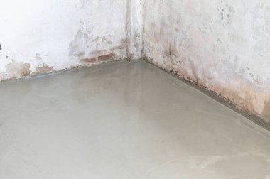 Pürüzsüz olması için yere çimento dökülüyor.