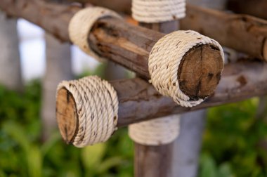 Kütükler birkaç tahta parçasına bağlanmış kaba kenevir ipleriyle bağlanmış.