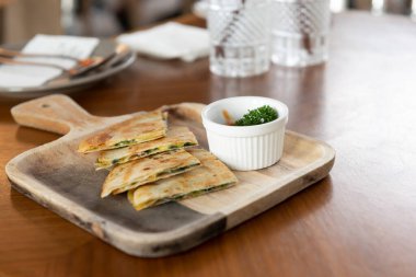 Tahta tabaklarda çıtır çıtır pizza ve sofra takımında sos kabı.